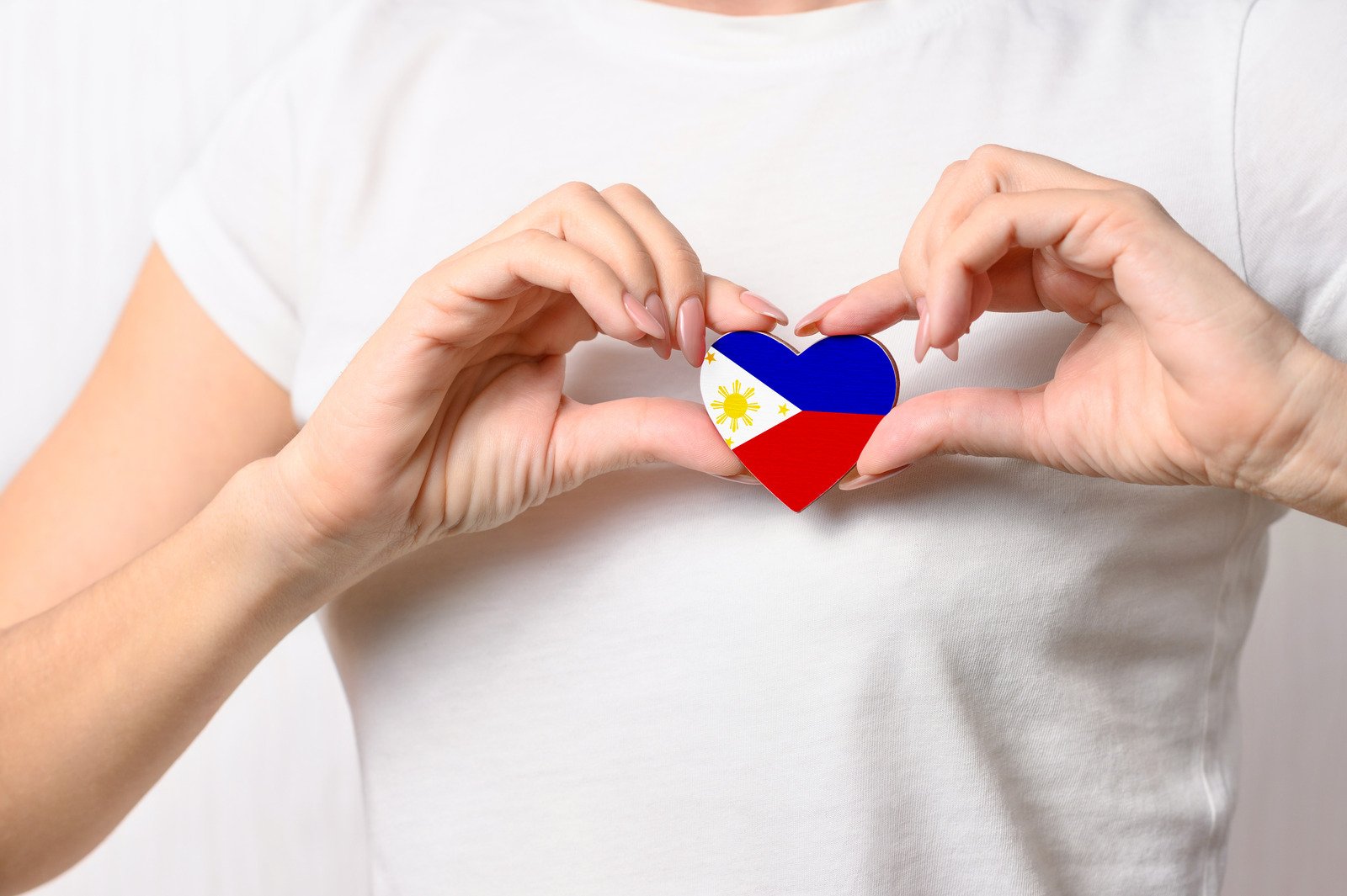 Hands forming a heart shape around a Philippines-flag heart pin