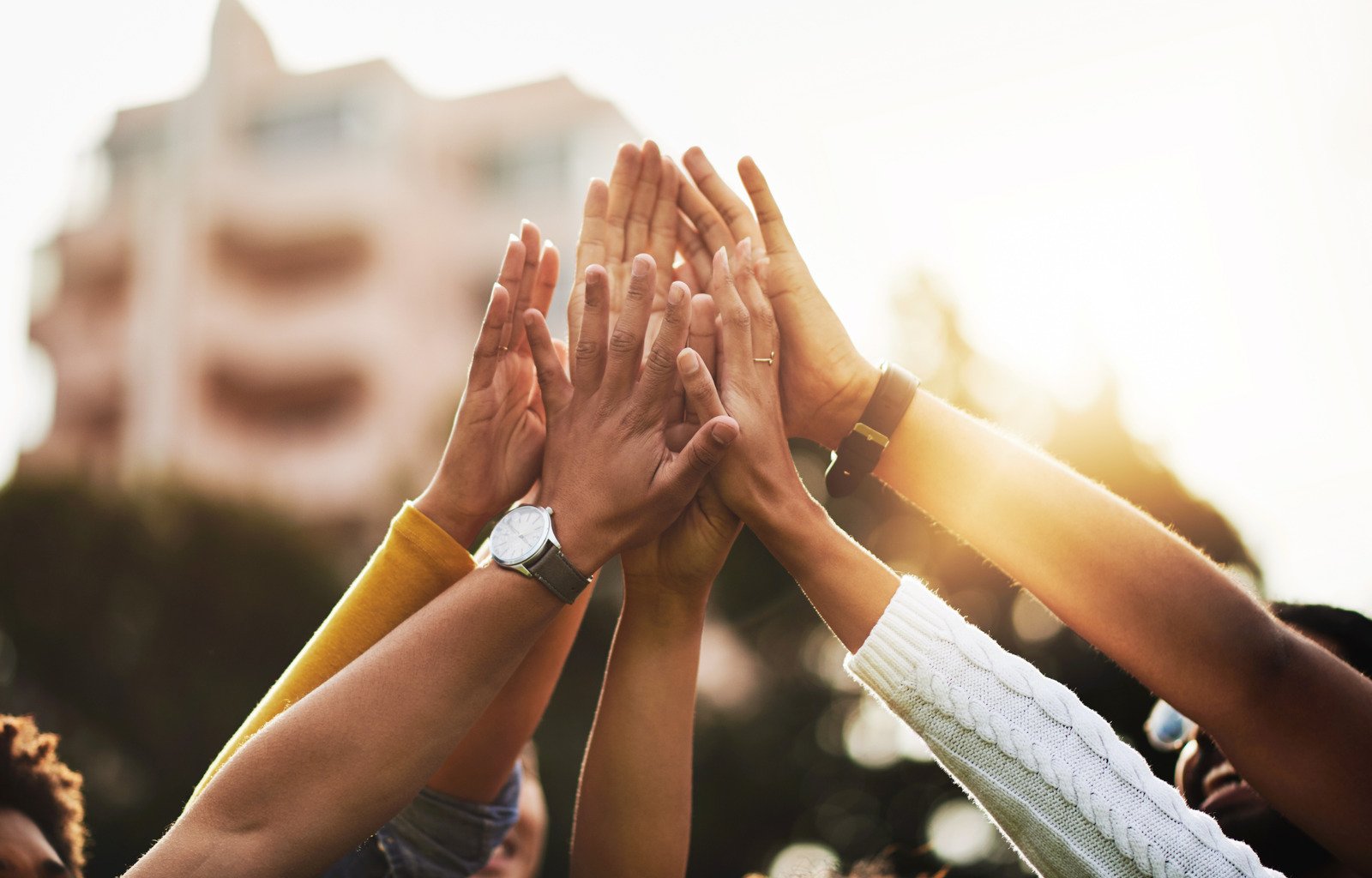 A group of hands reaching up to meet in a high-five