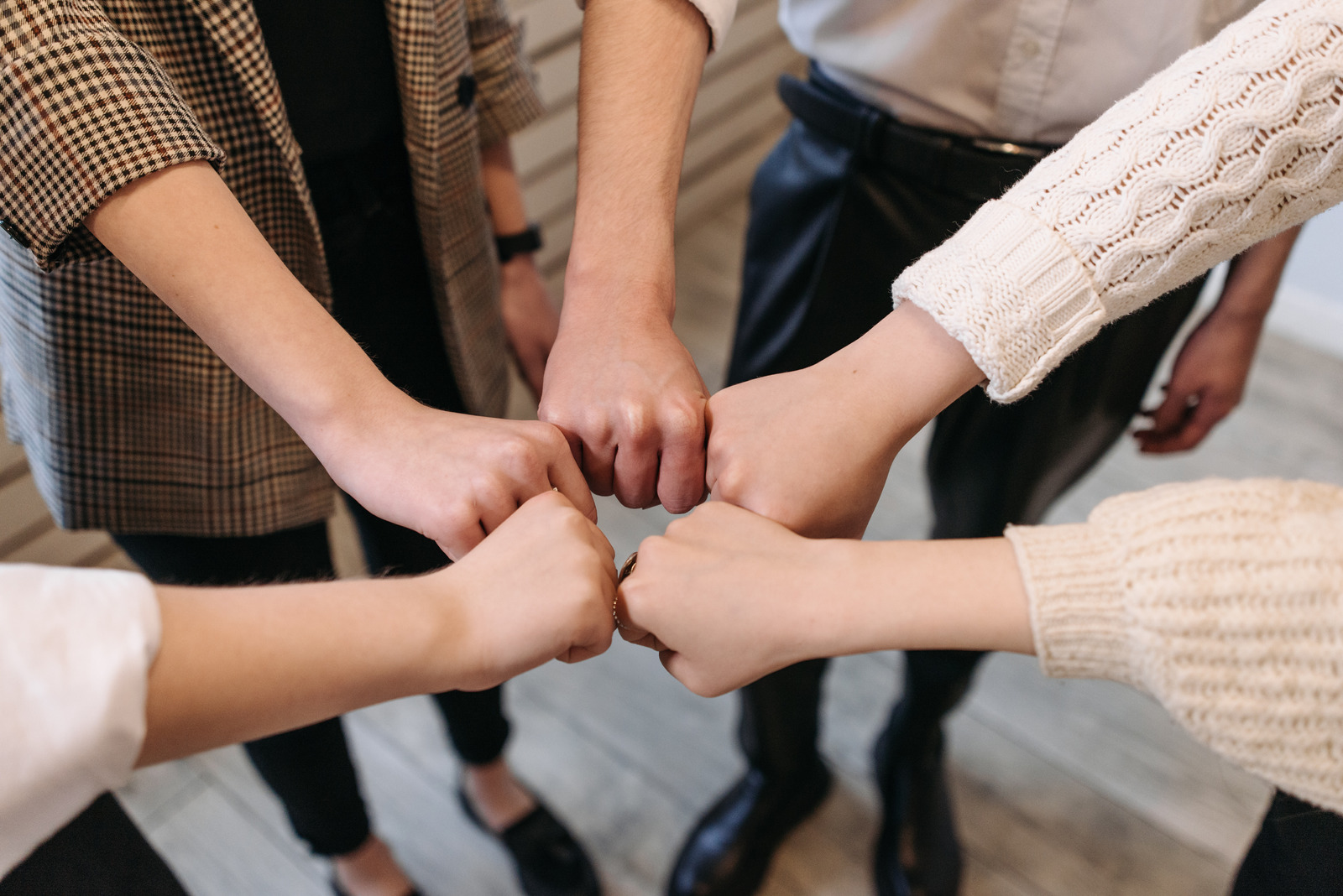 A group of people placing their fists together in a circle, representing bayanihan and unity